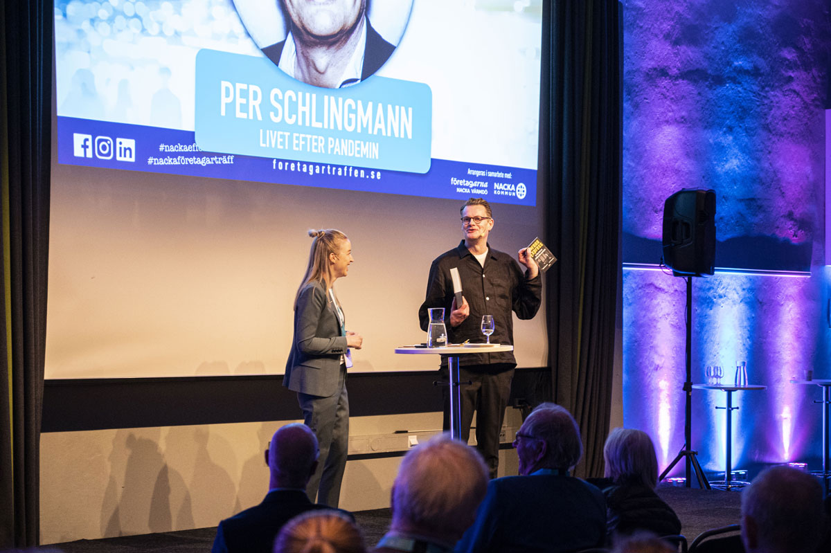 Per Schlingmann håller upp sin bok Coronaexpress, med Amanda Svensson på Nacka Företagarträff
